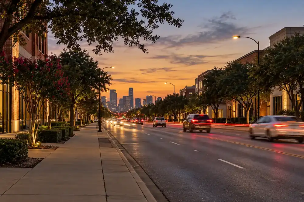 Wide boulevard at dusk with distant downtown towers and streaks of traffic lights