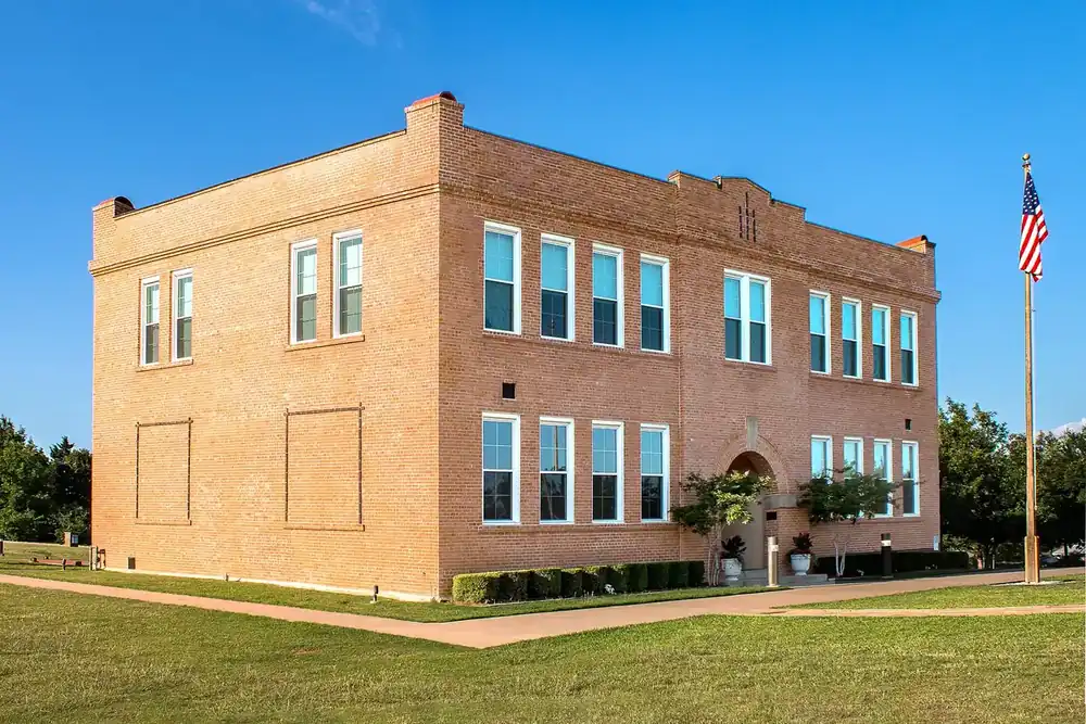 Historic two-story brick school building with an American flag in Bedford, Texas