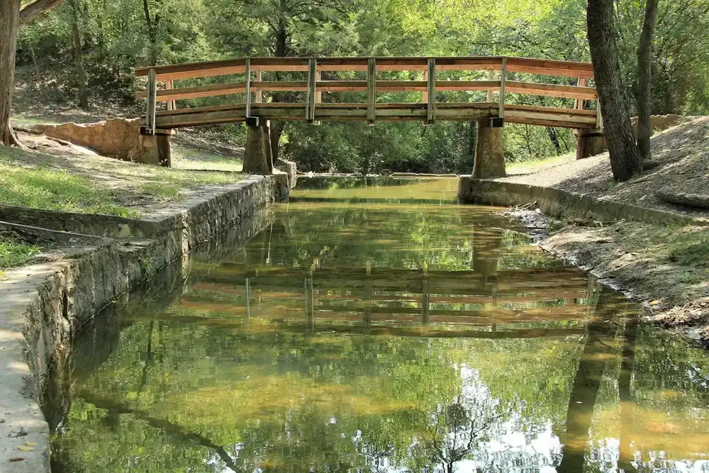 Wooden footbridge over a stone-lined creek in Grapevine Springs Preserve in Coppell, Texas